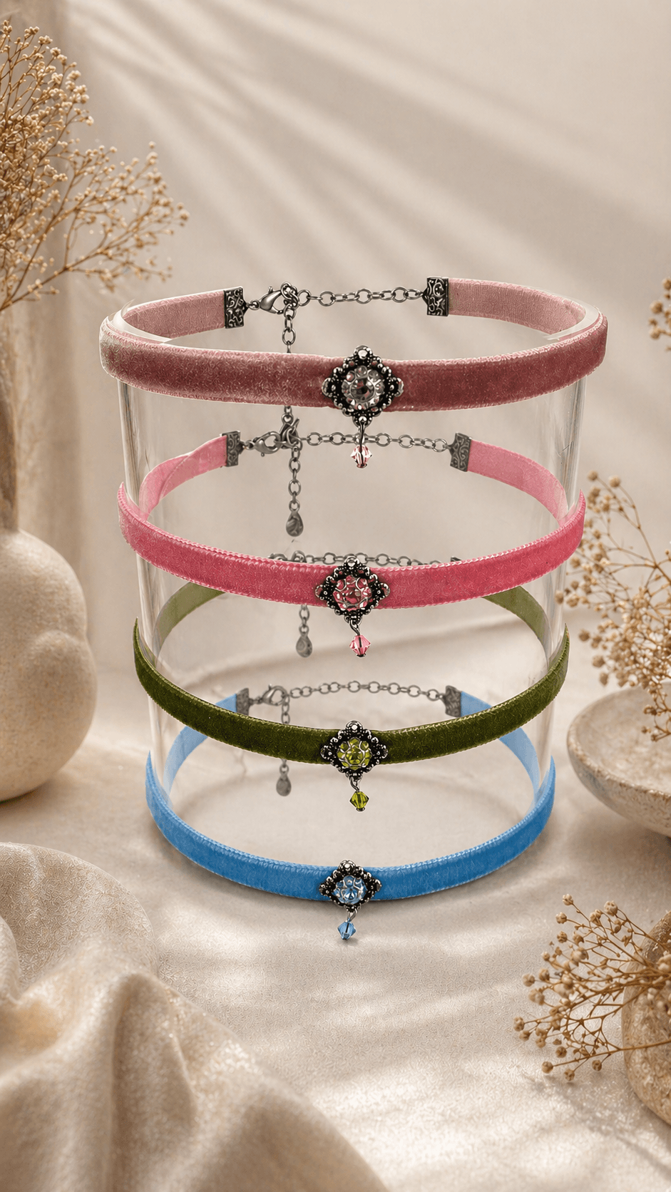 Vier elegante Samt-Choker in Rosa, Pink, Grün und Blau mit funkelnden Schmuckanhängern auf Glas.